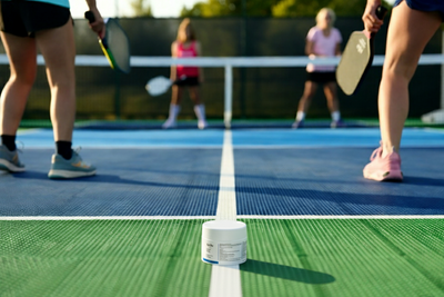 People playing pickleball on a court with a focus on Sol Rx in the foreground.